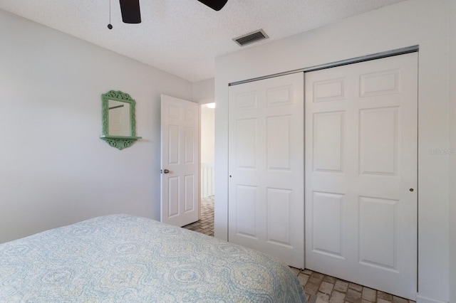 bedroom featuring a closet, ceiling fan, and a textured ceiling