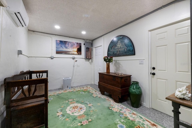 living area featuring a textured ceiling and a wall mounted AC