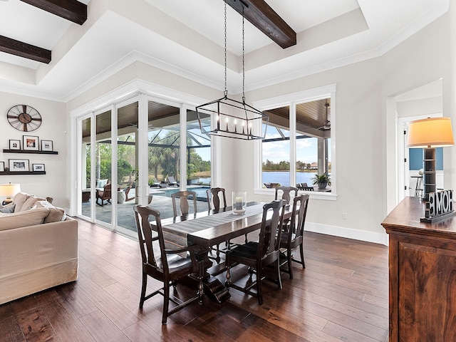 dining space with an inviting chandelier, dark hardwood / wood-style floors, a raised ceiling, a water view, and crown molding