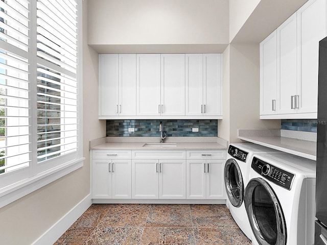 washroom featuring washing machine and dryer, cabinets, and sink