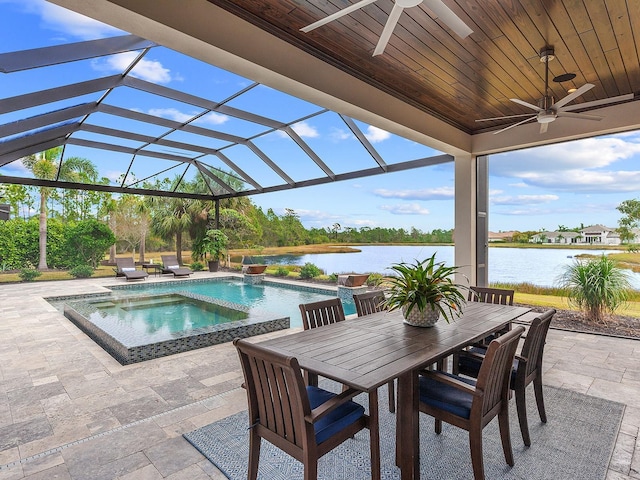 view of patio / terrace featuring a water view, a swimming pool with hot tub, ceiling fan, and glass enclosure