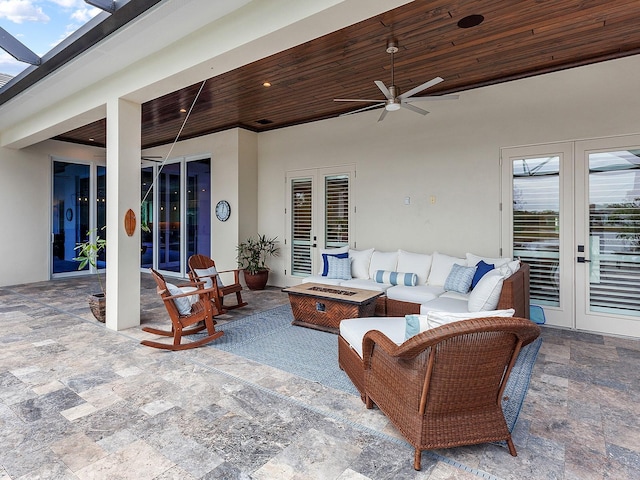 view of patio / terrace with ceiling fan, an outdoor living space with a fire pit, and french doors