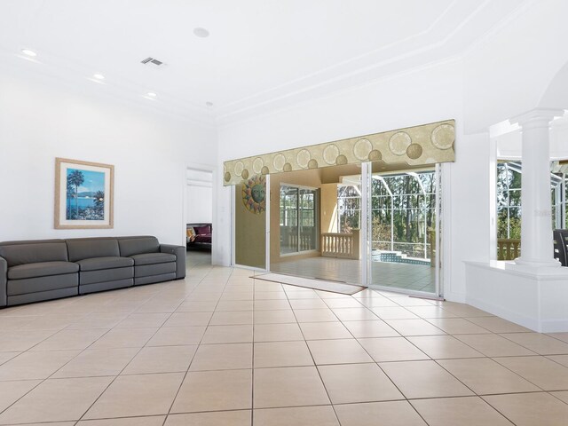 unfurnished living room with decorative columns, light tile patterned floors, ornamental molding, and a towering ceiling