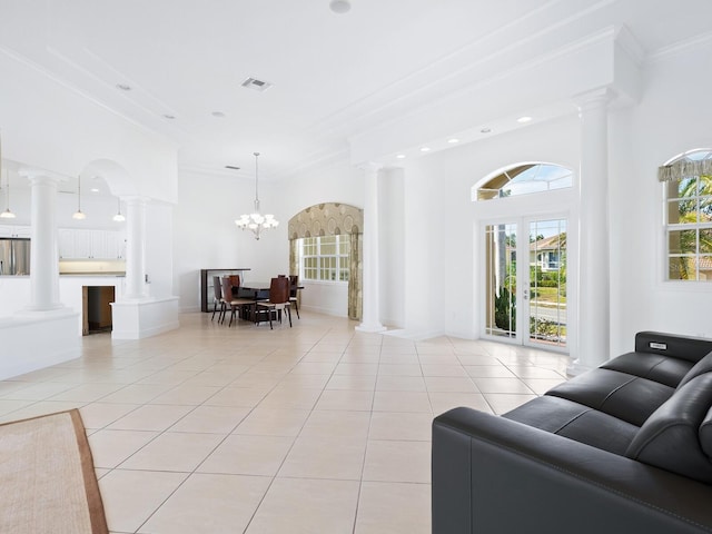 living room featuring decorative columns, crown molding, light tile patterned floors, and an inviting chandelier