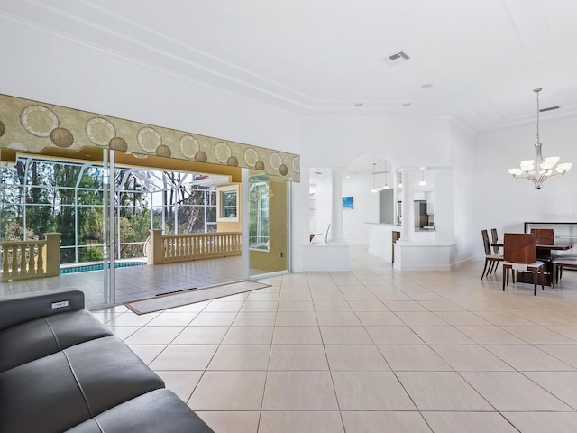 living room featuring decorative columns, an inviting chandelier, crown molding, and light tile patterned flooring