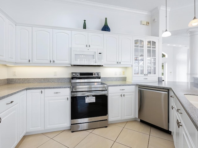 kitchen with appliances with stainless steel finishes, light tile patterned floors, white cabinets, decorative light fixtures, and ornamental molding