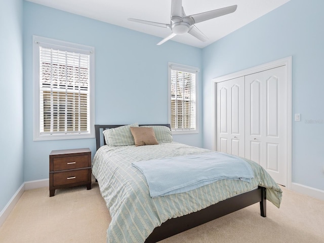 bedroom with a closet, ceiling fan, and light colored carpet