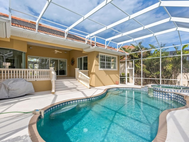 view of swimming pool featuring ceiling fan, glass enclosure, an in ground hot tub, and a patio area