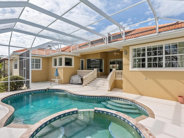 view of pool with glass enclosure, an in ground hot tub, and a patio area