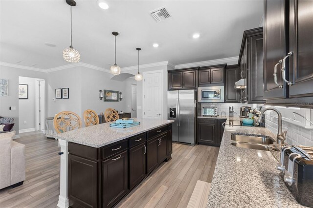 kitchen featuring decorative light fixtures, a kitchen island, appliances with stainless steel finishes, and sink