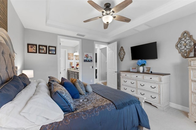 carpeted bedroom with ensuite bathroom, a raised ceiling, and ceiling fan