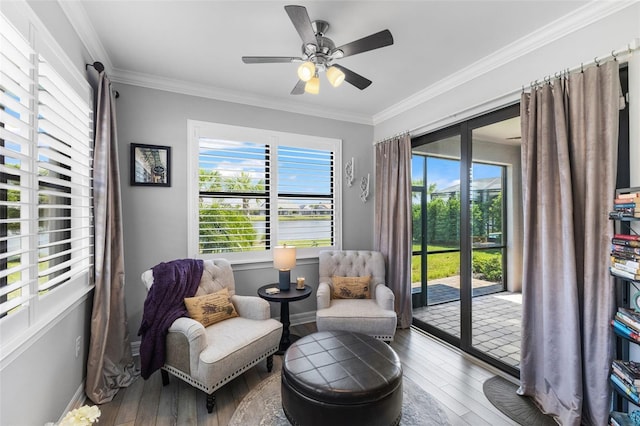 sitting room with ceiling fan, wood-type flooring, ornamental molding, and a wealth of natural light