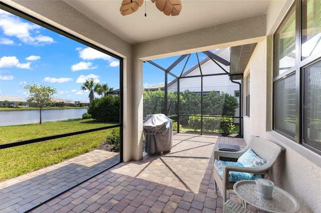 sunroom / solarium with ceiling fan and a water view