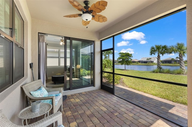 sunroom featuring ceiling fan and a water view