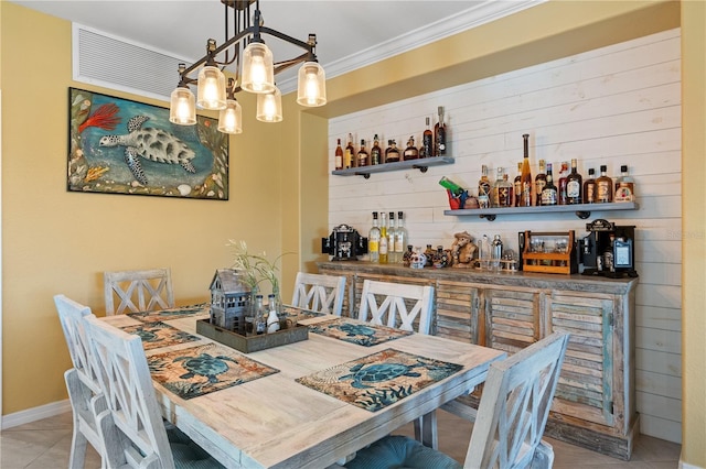 dining room featuring tile patterned flooring, ornamental molding, wooden walls, and bar area