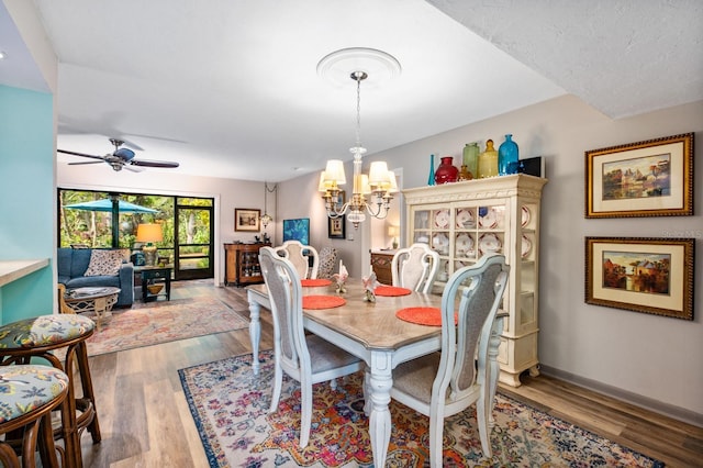 dining area featuring ceiling fan with notable chandelier and hardwood / wood-style flooring