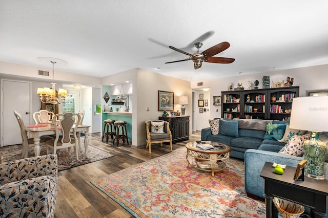 living room with ceiling fan with notable chandelier and dark hardwood / wood-style floors