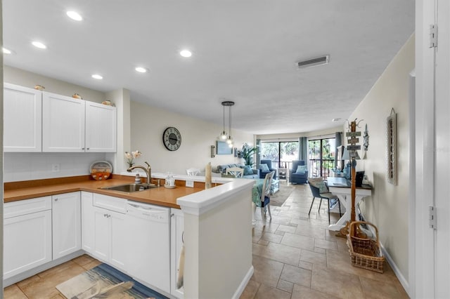 kitchen featuring kitchen peninsula, decorative light fixtures, white dishwasher, white cabinets, and sink