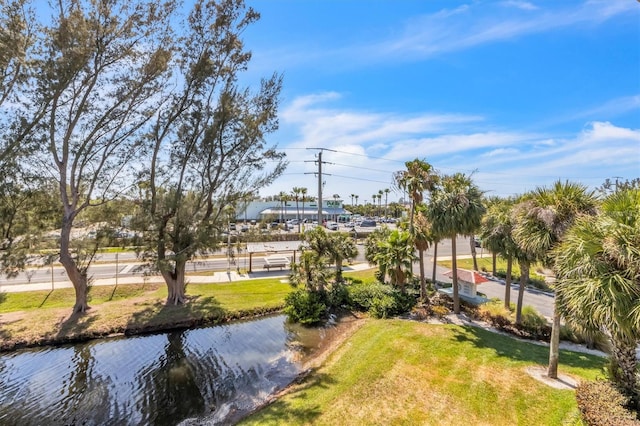 surrounding community with a water view and a yard