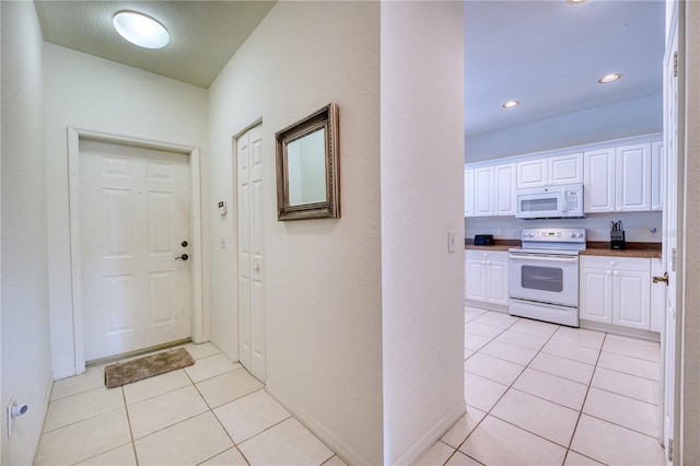 kitchen with white cabinetry, white appliances, and light tile patterned floors