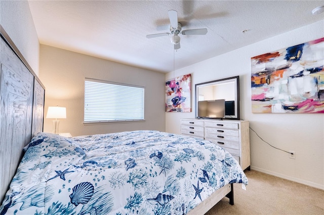 bedroom with ceiling fan, light colored carpet, and a textured ceiling