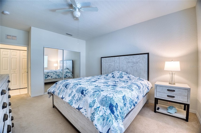 bedroom with ceiling fan, light colored carpet, and a closet