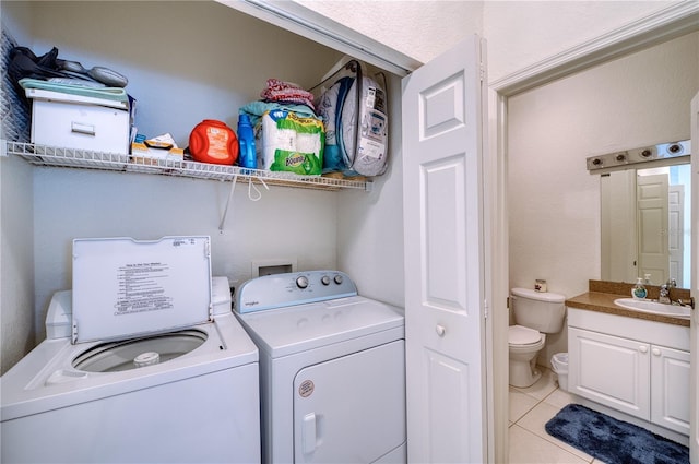 clothes washing area featuring light tile patterned flooring, washing machine and clothes dryer, and sink