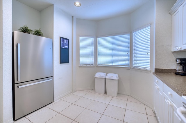 kitchen featuring light tile patterned floors, white cabinetry, and stainless steel refrigerator