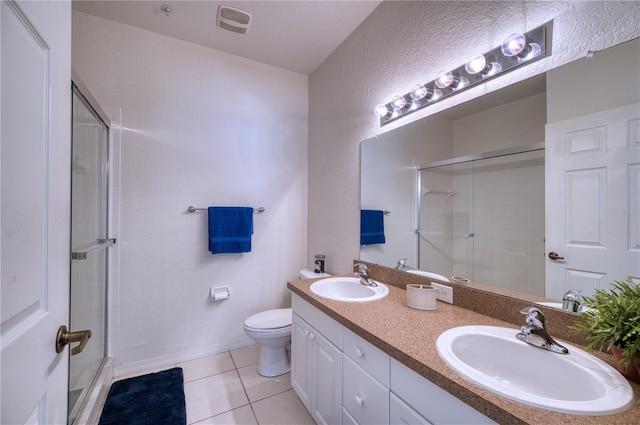 bathroom with tile patterned floors, a shower with door, toilet, and vanity