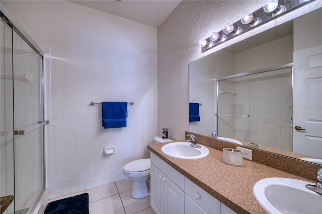 bathroom with tile patterned floors, a shower with door, toilet, and vanity