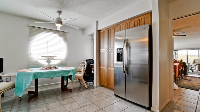 kitchen featuring a textured ceiling, ceiling fan, stainless steel fridge, and light tile patterned floors