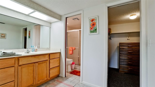 bathroom featuring toilet, vanity, a textured ceiling, and a shower with shower door