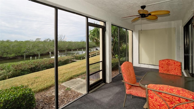 sunroom featuring ceiling fan and a water view