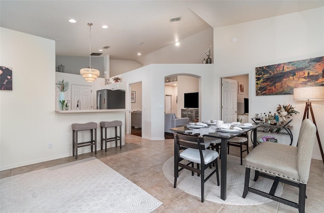 tiled dining space featuring high vaulted ceiling