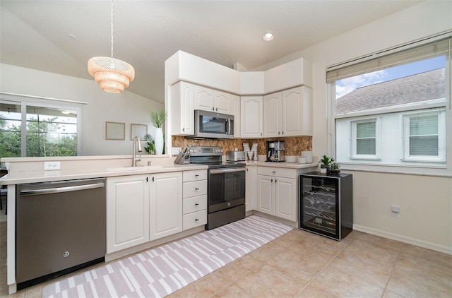 kitchen featuring stainless steel appliances, sink, white cabinetry, decorative backsplash, and beverage cooler