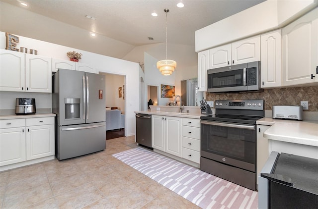 kitchen with vaulted ceiling, appliances with stainless steel finishes, white cabinets, decorative light fixtures, and tasteful backsplash