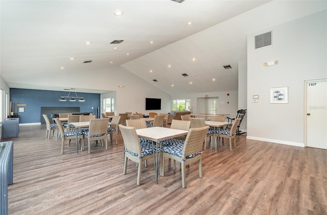 dining room featuring high vaulted ceiling and light hardwood / wood-style flooring