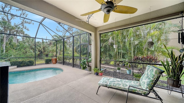 view of swimming pool with glass enclosure, ceiling fan, and a patio