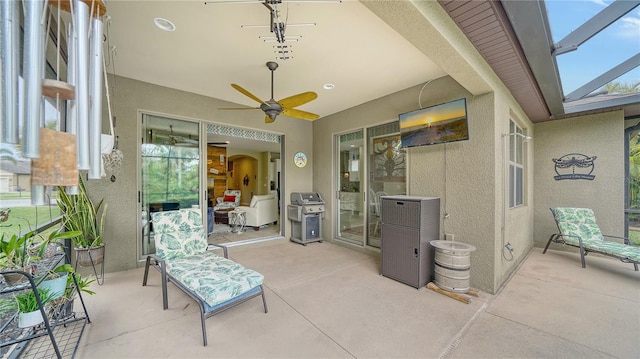 view of patio featuring glass enclosure, a grill, and ceiling fan