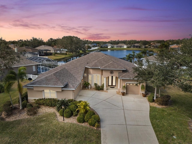 view of front of home featuring a garage, a water view, and a lawn