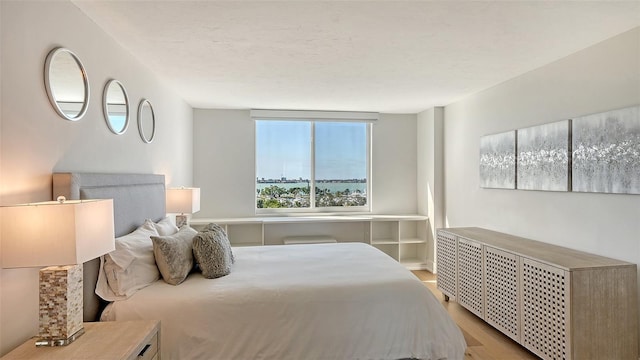 bedroom featuring radiator heating unit and light wood-type flooring