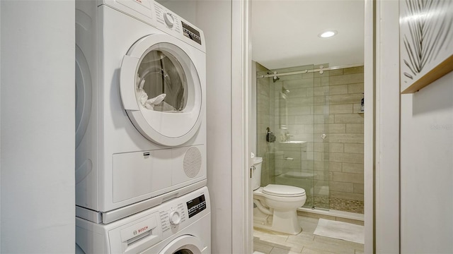 bathroom with stacked washer and dryer, tile patterned flooring, a shower with door, and toilet