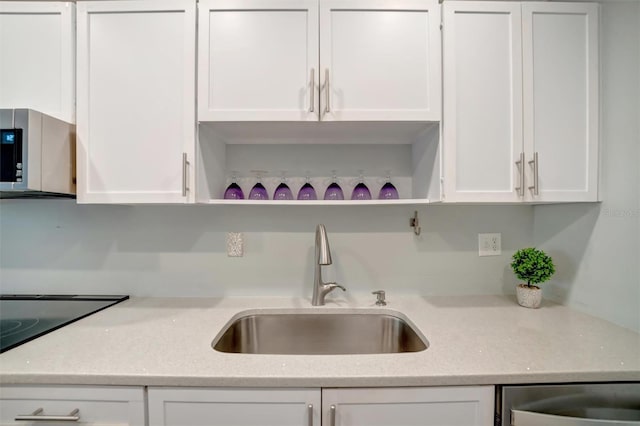 kitchen with sink, light stone countertops, and white cabinets