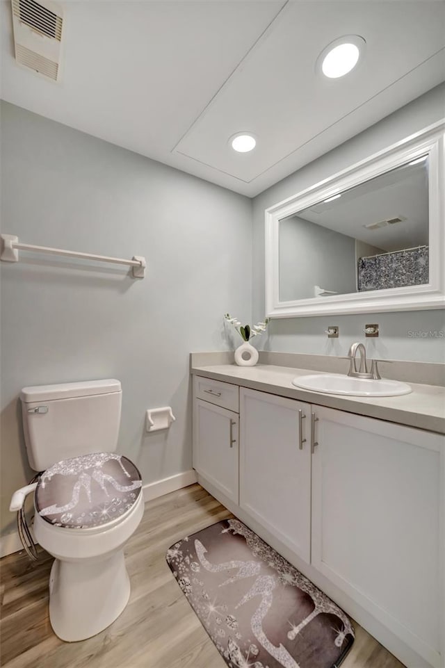 bathroom with wood-type flooring, vanity, and toilet