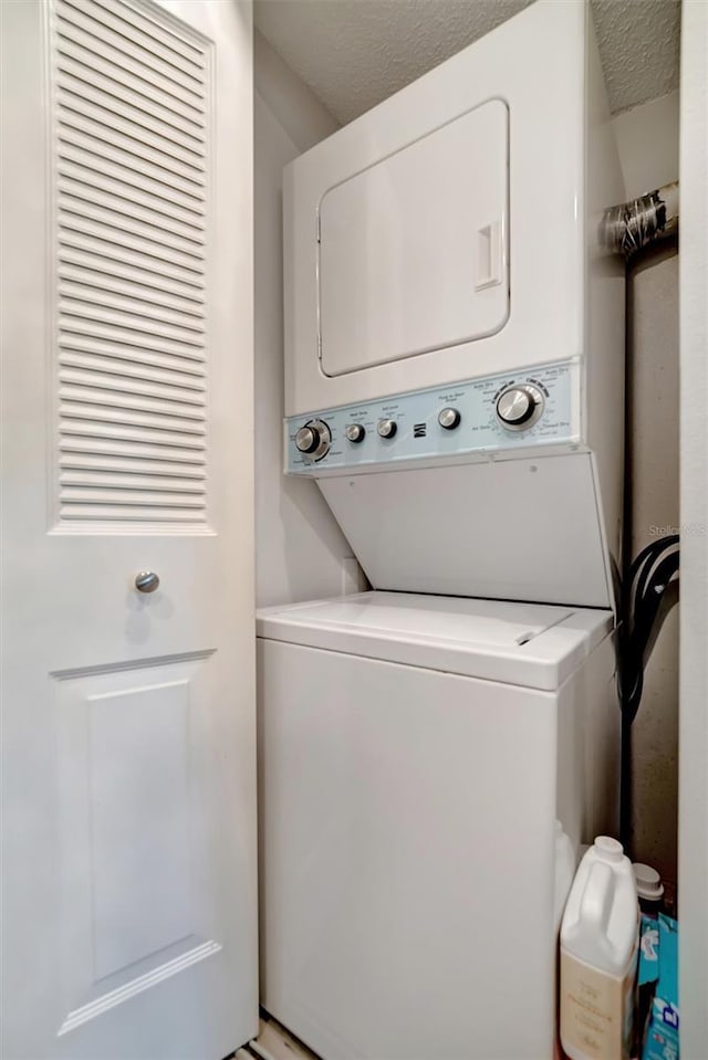 washroom with stacked washer and clothes dryer and a textured ceiling