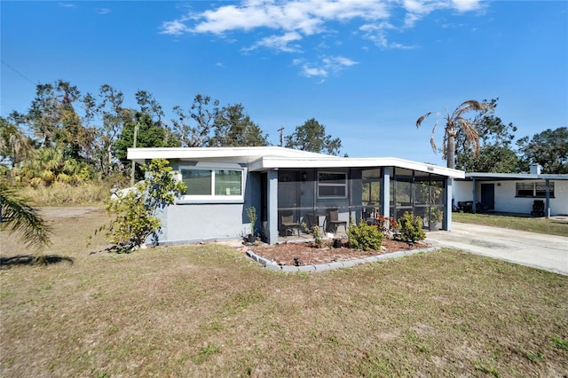 view of front of home featuring a carport, a sunroom, and a front yard