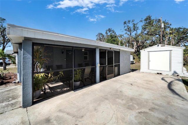 view of patio with a storage unit and a sunroom