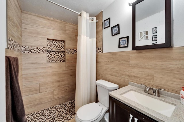 bathroom with vanity, toilet, tile walls, and walk in shower