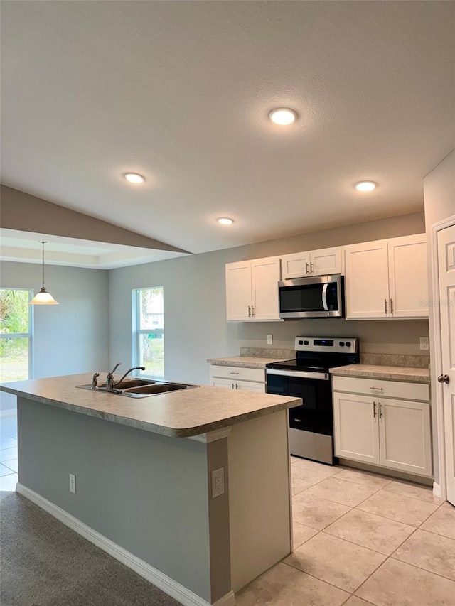 kitchen featuring white cabinets, decorative light fixtures, stainless steel appliances, an island with sink, and sink