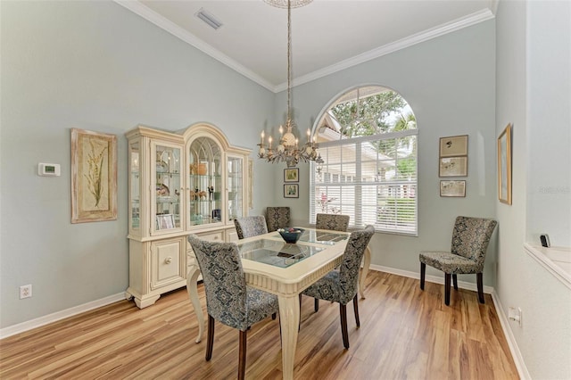 dining room featuring a high ceiling, crown molding, a notable chandelier, and light hardwood / wood-style flooring